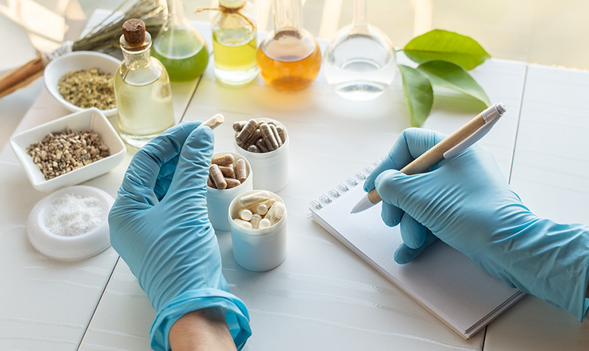 Dietary supplement capsules. Hand of a pharmacist writes in a notebook